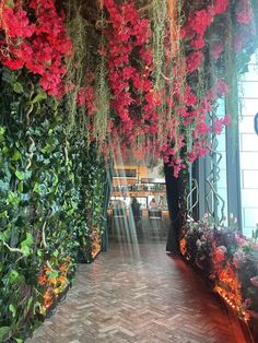 an indoor garden with flowers and greenery hanging from the ceiling