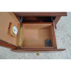 an open drawer with a clock on the top and a measuring tape in between it