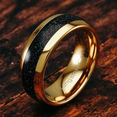 a gold and black wedding ring on top of a wooden table