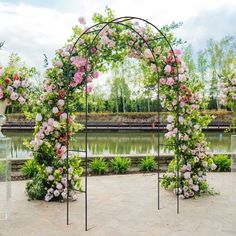 an outdoor wedding ceremony with pink flowers on the arch and greenery in the background