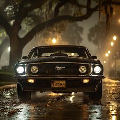 an old mustang car is parked on the side of the road in the rain at night