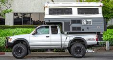 a truck with a camper attached to it's bed parked in front of a building