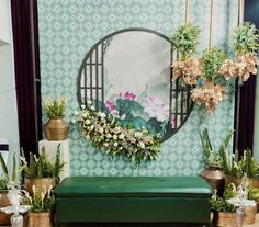 a green bench sitting under a mirror next to potted plants