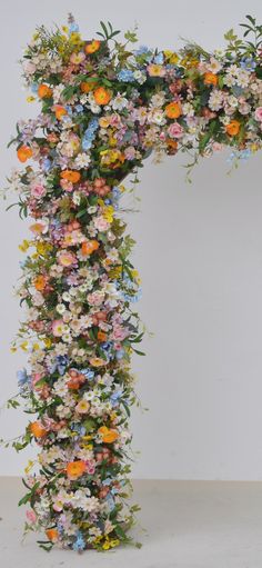 an arch made out of flowers on a white background with the letter t in it