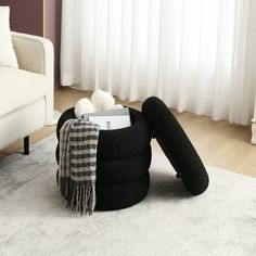 a living room with a white couch and black bean bag on the floor in front of a window