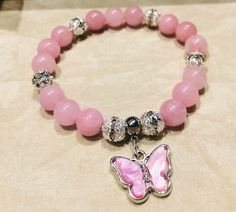 This lovely 8mm pink rhodonite beaded bracelet embodies the sweetness and charm of a blooming garden. The soft, blush-like hue of the rhodonite stones exudes a gentle, feminine elegance, while the delicate beads add a touch of whimsy and playfulness. Each stone is carefully selected to showcase its natural beauty, creating a bracelet that radiates warmth and tenderness. Perfect for those who appreciate the beauty of soft colors and delicate design. Gentle Feminine, Pink Rhodonite, Crystal Bead Jewelry, Feminine Elegance, Blooming Garden, Pink Vibes, Delicate Design, Butterfly Charm, Soft Colors