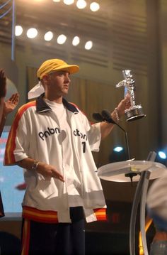 a man standing in front of a microphone holding a trophy