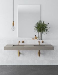 two sinks and a mirror in a white tiled bathroom with gold faucets on the wall