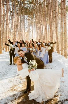 a bride and groom posing for a wedding photo in the snow with their bridal party