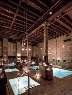 an indoor swimming pool is lit up with candles in the dark and surrounded by brick walls