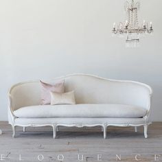 a white couch sitting next to a chandelier on top of a wooden floor