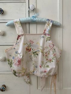 a baby's bib hanging on a white door with blue handles and flowers