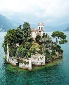 an island in the middle of water with trees on it and a building on top