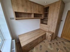 an empty room with wooden cabinets and drawers in the corner, next to a window