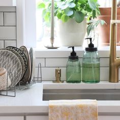 a kitchen sink with soap dispensers and dishes in front of a window