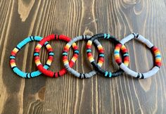 four bracelets with different colored beads on top of a wooden table