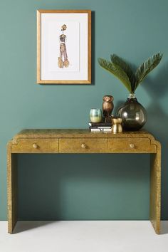 a table with two vases and a plant on it in front of a painting