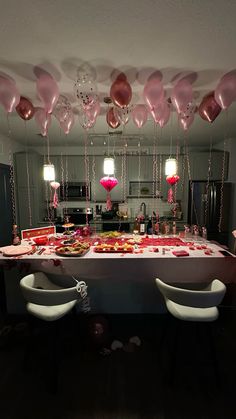 the table is set up for a valentine's day party with pink balloons hanging from the ceiling