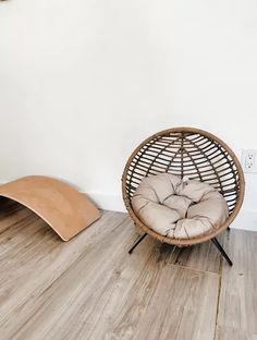 a wicker chair sitting on top of a hard wood floor next to a wall