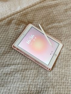 an electronic device sitting on top of a bed next to a pen and paper holder