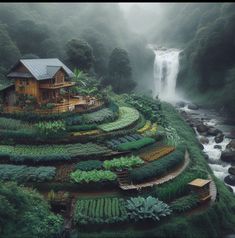 an aerial view of a house in the middle of a lush green valley with a waterfall behind it