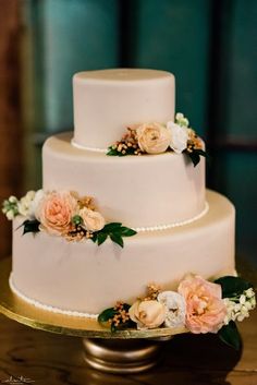 a three tiered white cake with flowers on top