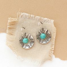 two pairs of earrings sitting on top of a piece of cloth