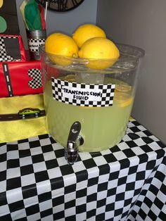 some lemons are sitting in a bucket on a checkered tablecloth with a black and white pattern