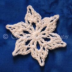 a crocheted snowflake is shown on a blue cloth with white thread