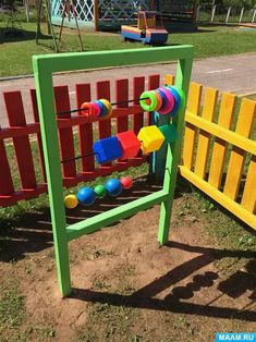 an outdoor play structure made out of plasticine and wooden slats with colorful balls on it