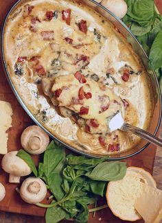 a casserole dish with mushrooms, spinach and cheese on a cutting board