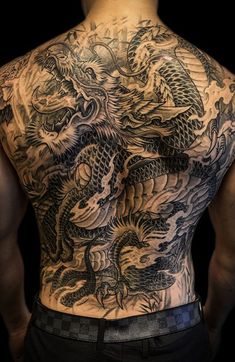 the back of a man with tattoos on his body and dragon tattoo designs on his chest