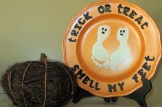 an orange plate with two ghost faces on it next to a ball of yarn that says trick or treat smell my feet