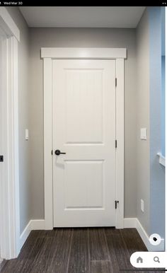 an empty room with a white door and wood flooring on the side of it