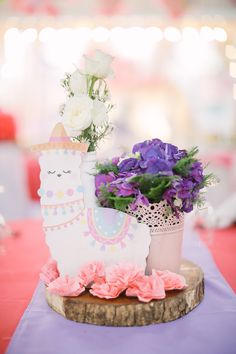 a table topped with a vase filled with purple and white flowers