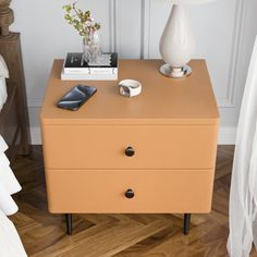 a nightstand with a cell phone on it next to a lamp