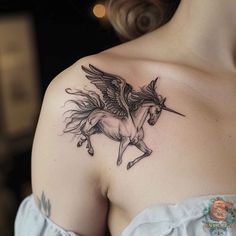 a woman with a black and white tattoo on her shoulder has a winged unicorn on it's back