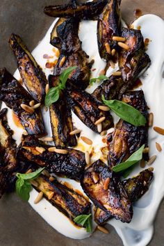 grilled eggplant and pine nuts on a white platter with garnish