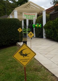 there is a sign that says crocodiles ahead in front of a gazebo with balloons