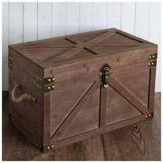 a large wooden box sitting on top of a wooden floor next to a white wall