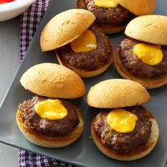 mini hamburgers with cheese on them sitting on a plate