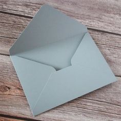 an open gray envelope sitting on top of a wooden table next to a piece of paper