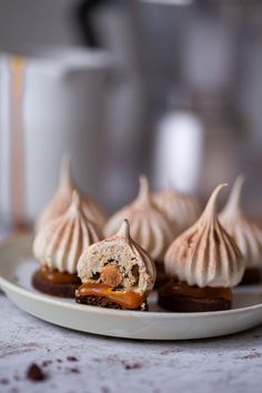 some desserts are on a white plate with coffee in the backgroung