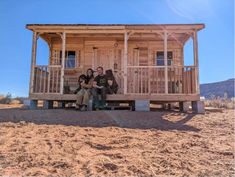 two people sitting on a bench in front of a small cabin