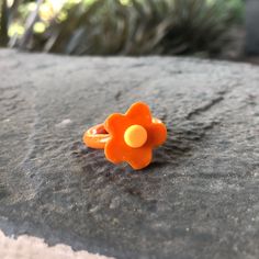 an orange flower ring sitting on top of a rock