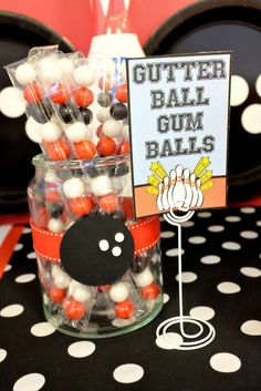 there is a glass jar with candy in it and a sign that says gutter ball gum balls