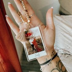 a woman's hand holding up a small photo and two bracelets on it