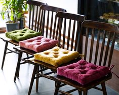 three wooden chairs with different colored cushions on them