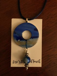 a necklace with a blue circle and bead hanging from it's end on a card