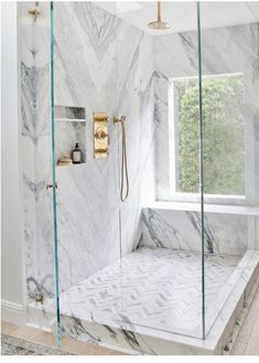 a bathroom with marble walls and flooring, shower head, and glass doored window